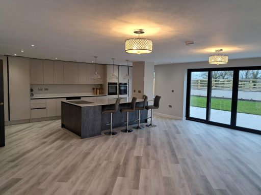 Modern kitchen with an island and bar stools, open to a spacious living area and garden view.